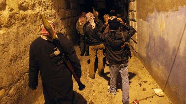 Syrian rebels walk in an alley in the city of Idlib in northwestern Syria on February 8, 2012.
