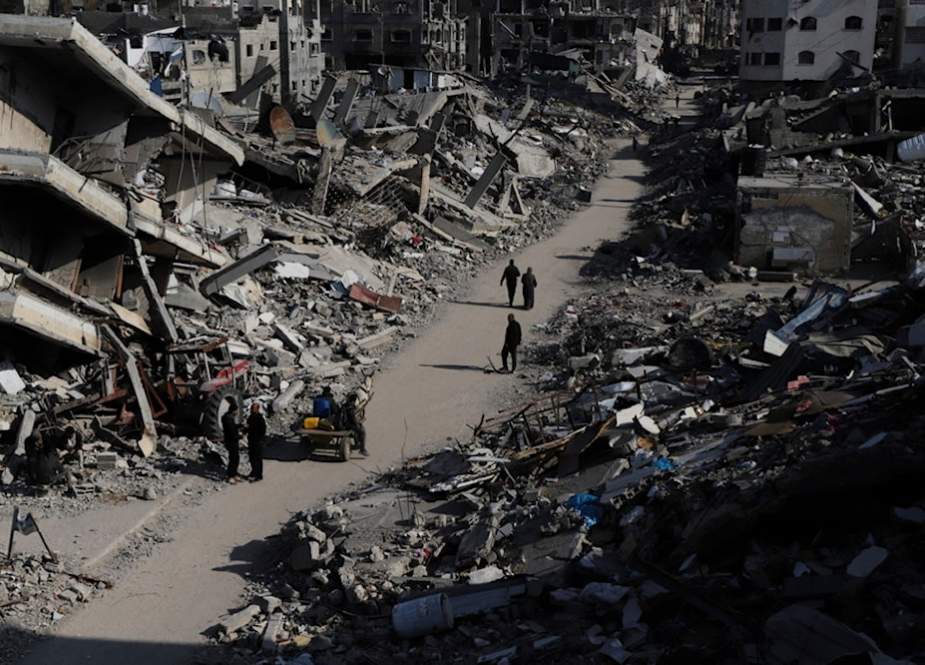 Palestinians walk through the destruction from the Israeli invasion of Jabaliya refugee camp in the Gaza Strip