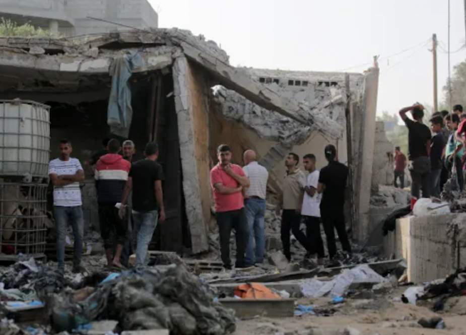 Palestinians gather outside a damaged house following Israeli bombardment