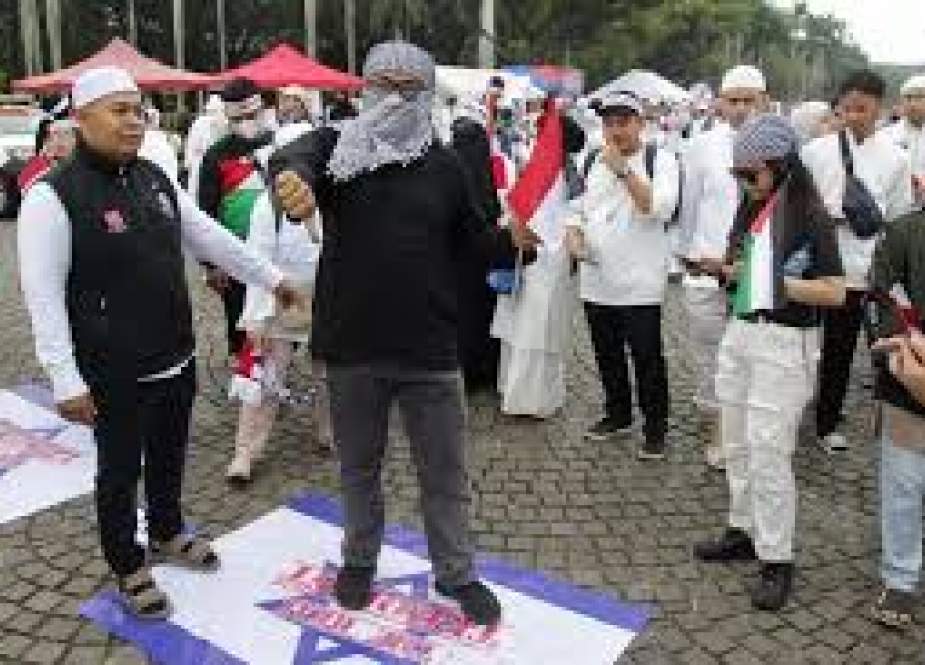 Warga yang tergabung dalam Aliansi Muslim Untuk Kemanusiaan (AMUK) menginjak bendera Israel