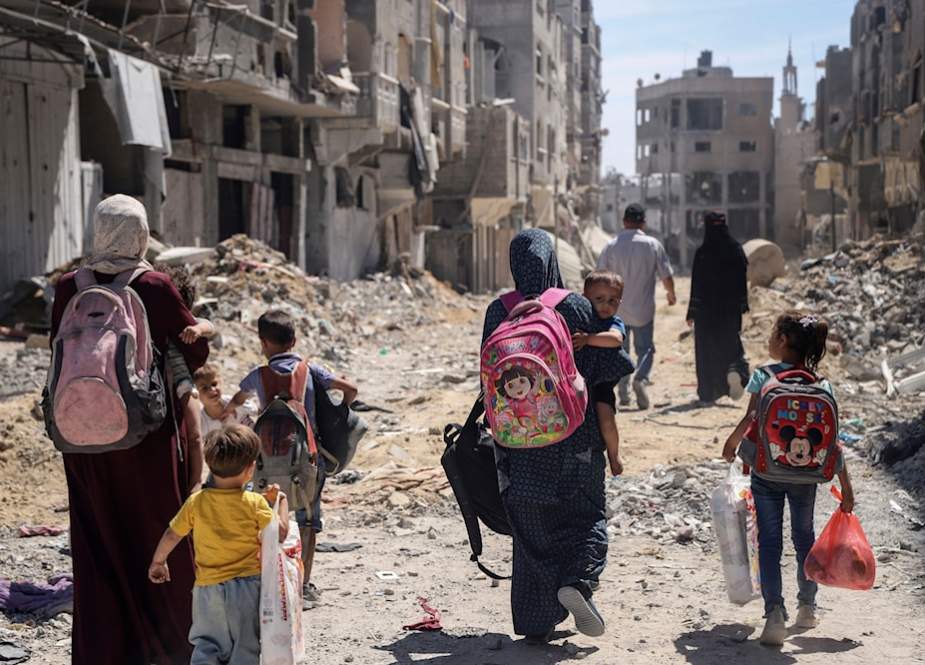 Palestinian women and their children walk through destruction in the wake of an Israeli air and ground offensive in Jabalia, northern Gaza Strip