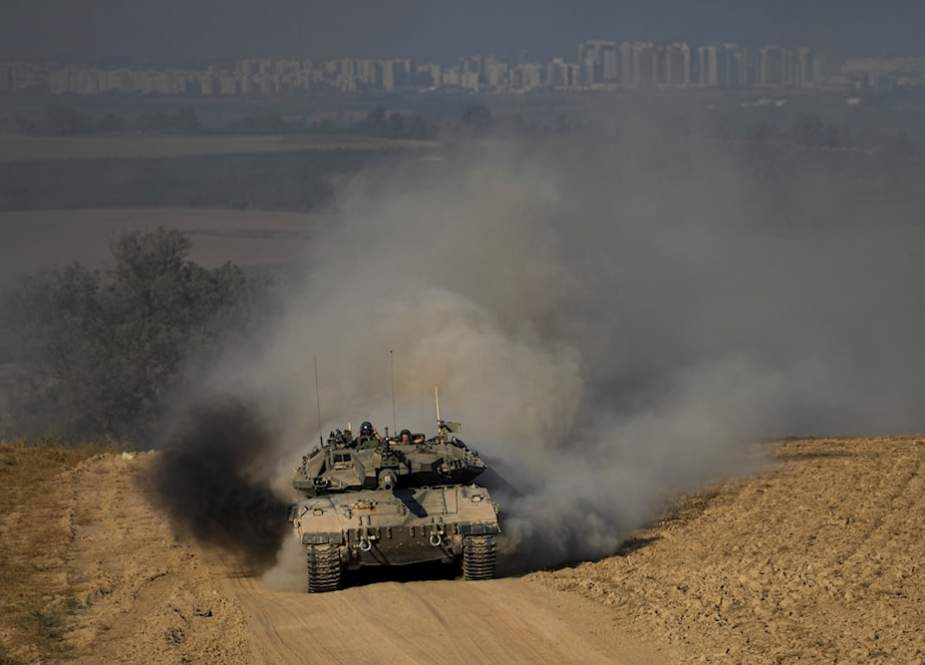 Israeli soldiers drive a tank near the Gaza Strip, in southern occupied Palestine