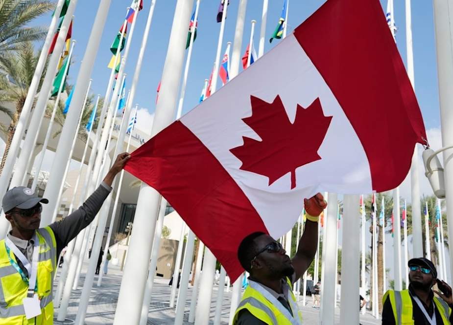 Workers adjust the flag of Canada ahead of the COP28 UN Climate Summit, in Dubai, United Arab Emirates