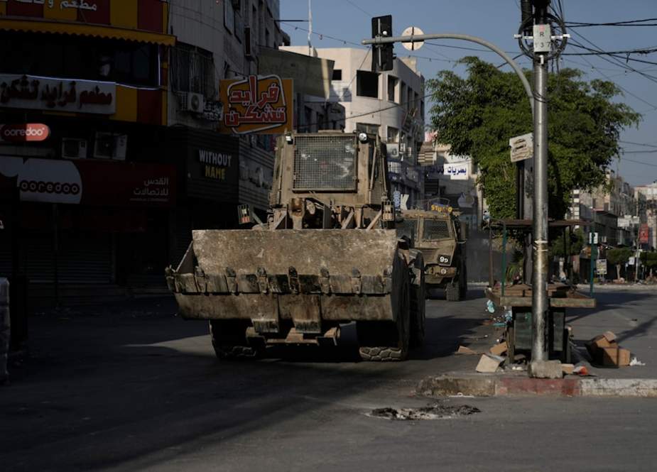 An Israeli bulldozer and an armored vehicle move on a street during a raid in the occupied West Bank city of Jenin