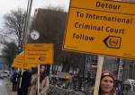 Amnesty International protesters hold signs pointing to the ICC along the route to the opening of a new National Holocaust Museum in Amsterdam, Netherlands